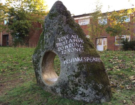 Classic Cornish granite holed stone in a public park with a hand carved Shakespearean quote